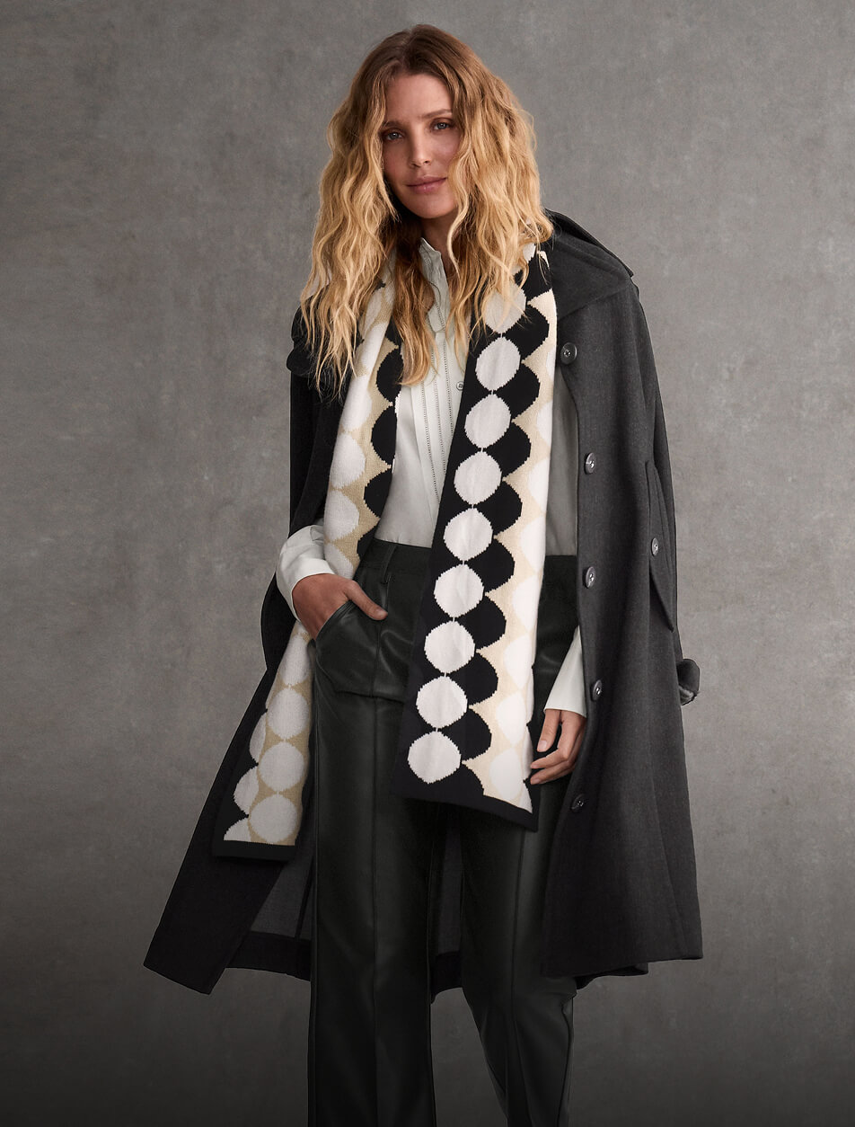 Female wearing a black and white patterned scarf with a long coat